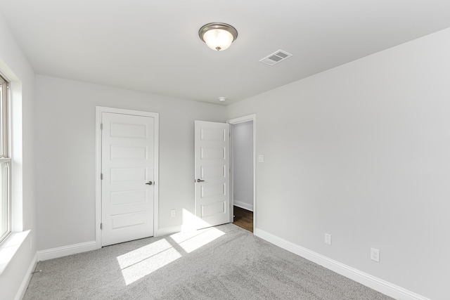 unfurnished bedroom with a closet, multiple windows, and carpet