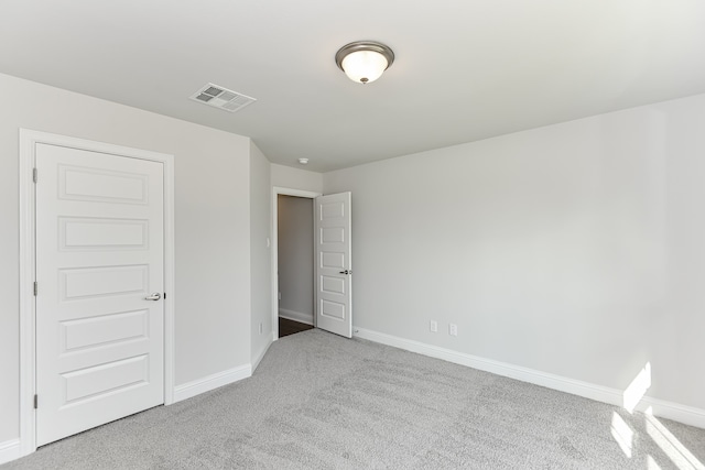 unfurnished bedroom with light colored carpet and a closet