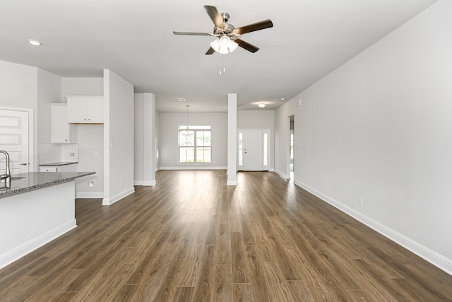 unfurnished living room with dark hardwood / wood-style floors, sink, and ceiling fan