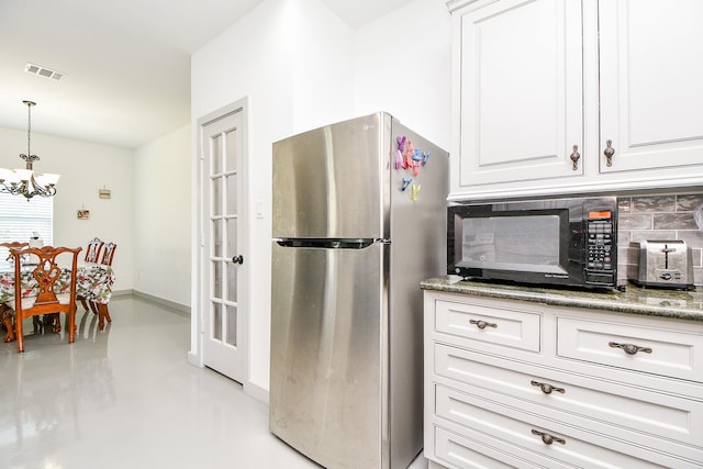 kitchen with tasteful backsplash, pendant lighting, a notable chandelier, white cabinets, and stainless steel refrigerator