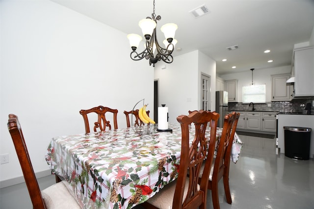 dining room with sink, concrete flooring, and a notable chandelier