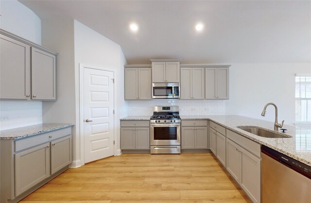 kitchen with sink, light wood-type flooring, stainless steel appliances, and backsplash