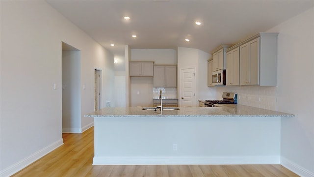 kitchen with sink, light hardwood / wood-style flooring, backsplash, stainless steel appliances, and kitchen peninsula