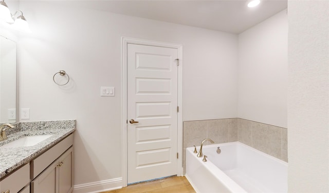 bathroom with hardwood / wood-style flooring, vanity, and a bathing tub