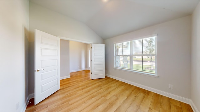 unfurnished bedroom featuring vaulted ceiling and light wood-type flooring