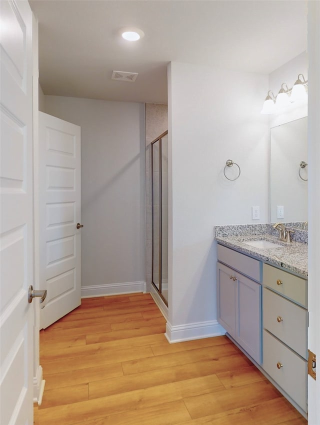 bathroom with an enclosed shower, vanity, and hardwood / wood-style flooring