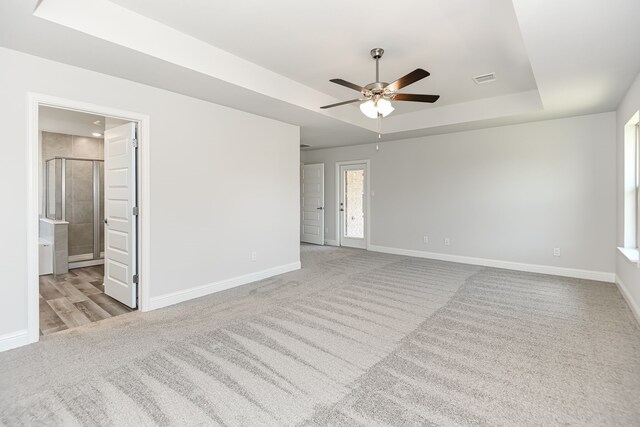 carpeted spare room featuring ceiling fan and a tray ceiling