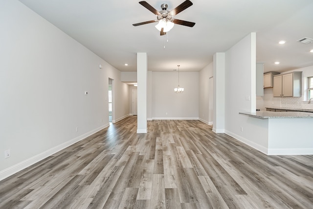 unfurnished living room with light hardwood / wood-style floors and ceiling fan with notable chandelier