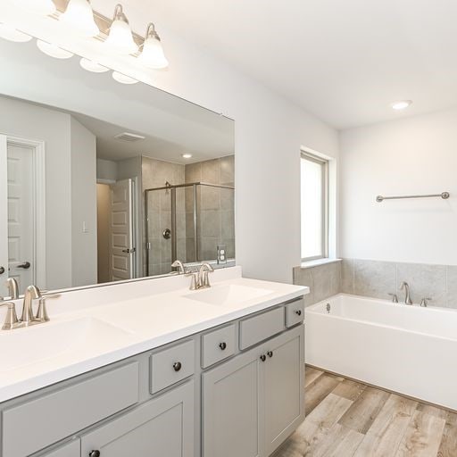 bathroom featuring shower with separate bathtub, hardwood / wood-style floors, and double vanity