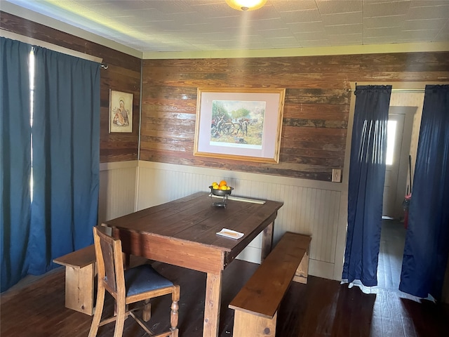 dining room with dark hardwood / wood-style flooring and wooden walls