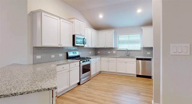 kitchen with appliances with stainless steel finishes, light hardwood / wood-style flooring, tasteful backsplash, sink, and light stone counters