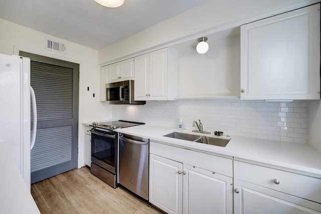 kitchen with decorative backsplash, white cabinetry, light wood-type flooring, stainless steel appliances, and sink