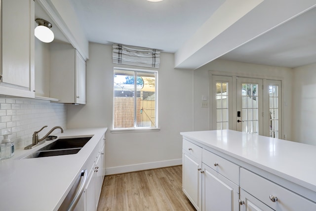 kitchen featuring light wood-type flooring, sink, white cabinets, and decorative backsplash