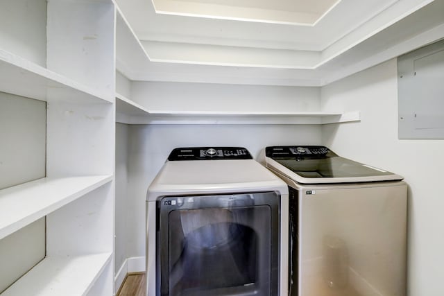 laundry room with washing machine and dryer, hardwood / wood-style flooring, and electric panel