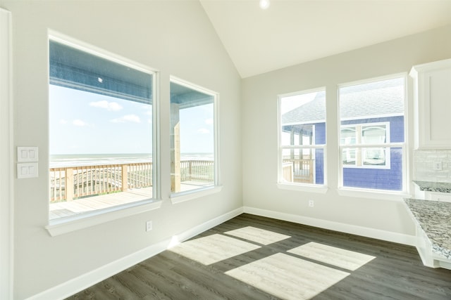 spare room with dark wood-type flooring and vaulted ceiling