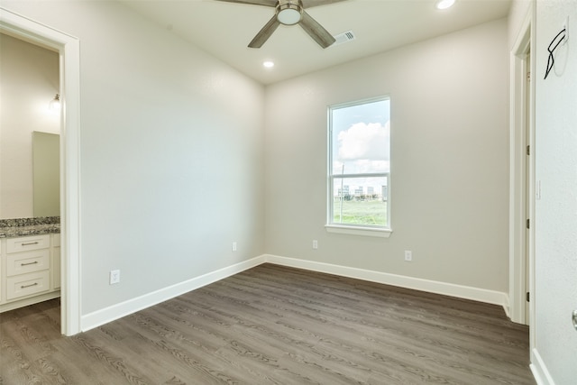 unfurnished bedroom with ceiling fan, dark wood-type flooring, and connected bathroom