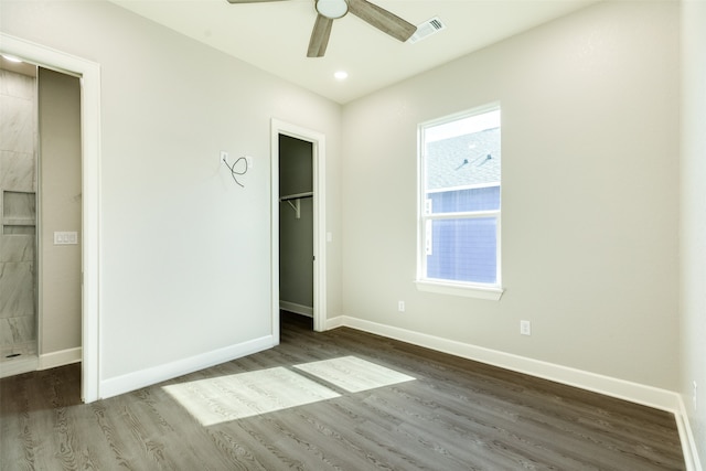 unfurnished bedroom featuring a spacious closet, ceiling fan, dark hardwood / wood-style flooring, and multiple windows