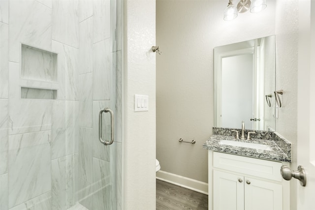 bathroom featuring wood-type flooring, vanity, toilet, and a shower with shower door