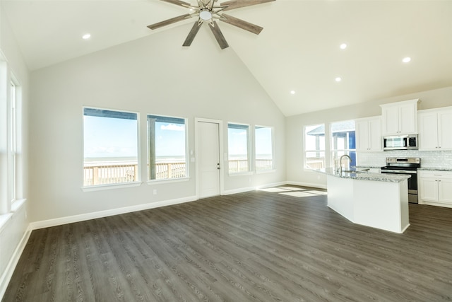 kitchen with stainless steel appliances, dark hardwood / wood-style flooring, an island with sink, and light stone counters