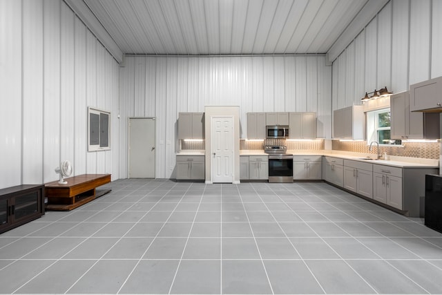 kitchen featuring gray cabinets, tasteful backsplash, sink, light tile patterned floors, and stainless steel appliances