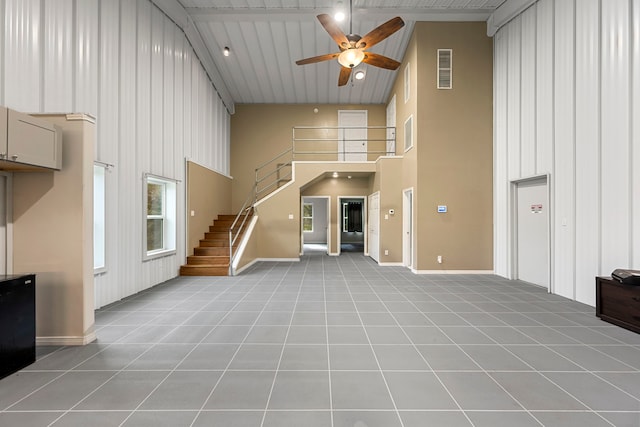 unfurnished living room featuring ceiling fan, a towering ceiling, and light tile patterned floors