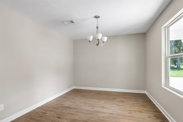 unfurnished room with light hardwood / wood-style flooring and a notable chandelier