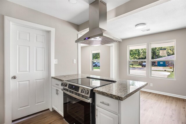 131 County Road 2364, Hardin, TX 77575 - kitchen featuring electric range, island exhaust hood, light wood-type flooring, light stone counters, and white cabinets