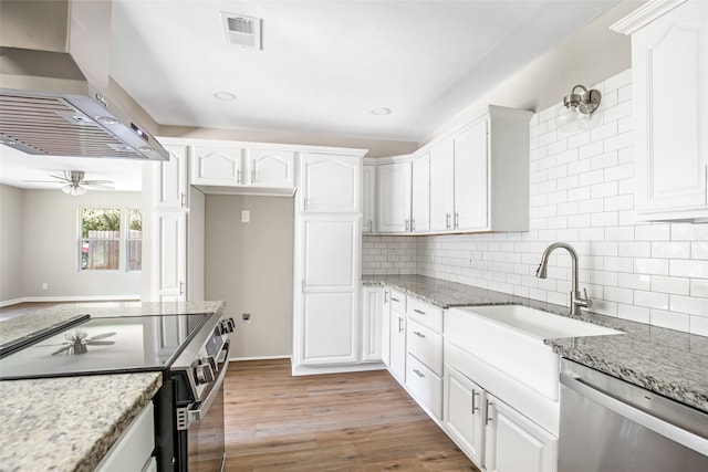 kitchen featuring wall chimney range hood, white cabinets, stainless steel appliances, and light hardwood / wood-style floors