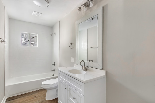 full bathroom featuring vanity, tiled shower / bath combo, wood-type flooring, and toilet