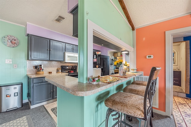 kitchen with a kitchen breakfast bar, kitchen peninsula, black refrigerator, backsplash, and range with electric stovetop