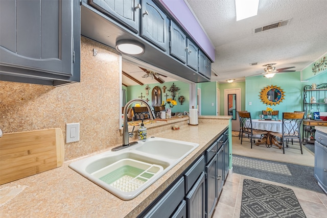 kitchen with sink, light tile flooring, ceiling fan, and a textured ceiling