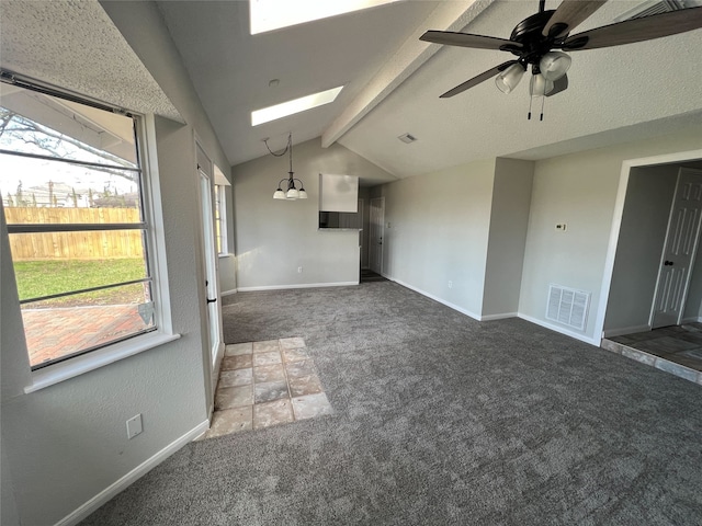 unfurnished living room featuring ceiling fan with notable chandelier, lofted ceiling with skylight, and dark colored carpet