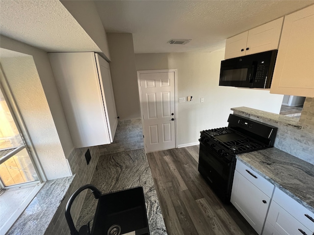 kitchen featuring light stone counters, a textured ceiling, dark wood-type flooring, white cabinets, and black appliances