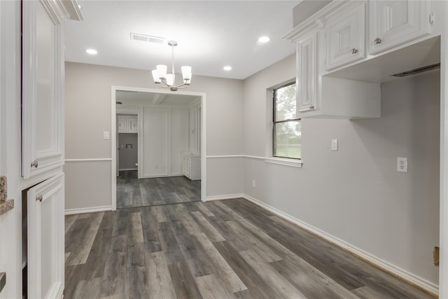 interior space featuring a chandelier, pendant lighting, white cabinets, and dark wood-type flooring