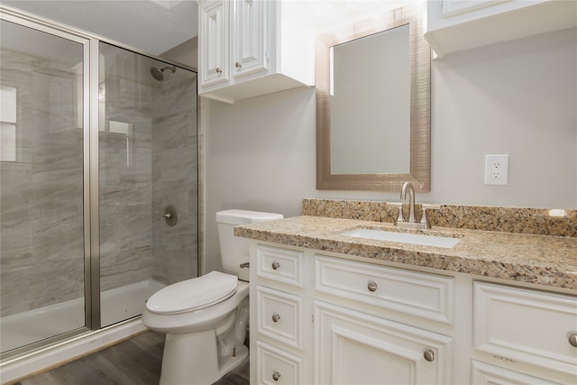 bathroom featuring wood-type flooring, toilet, vanity, and an enclosed shower