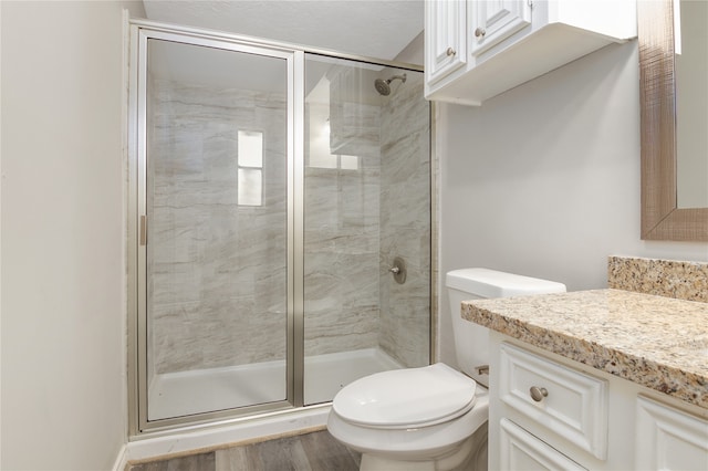 bathroom featuring vanity, a shower with door, toilet, and hardwood / wood-style floors