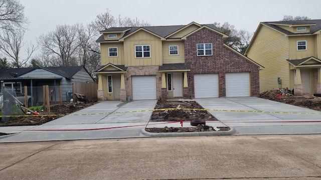 view of front facade with brick siding, board and batten siding, fence, driveway, and an attached garage