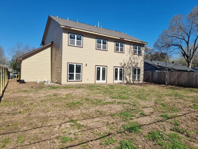 rear view of house featuring french doors, fence, and a lawn