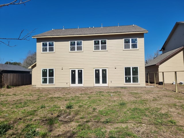 rear view of property featuring french doors, fence, and a lawn