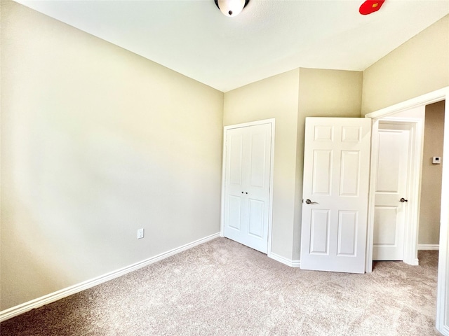 unfurnished bedroom with baseboards, carpet floors, and a closet