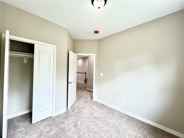 unfurnished bedroom with a closet, carpet flooring, and baseboards