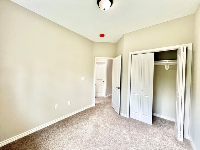 unfurnished bedroom featuring light colored carpet and a closet