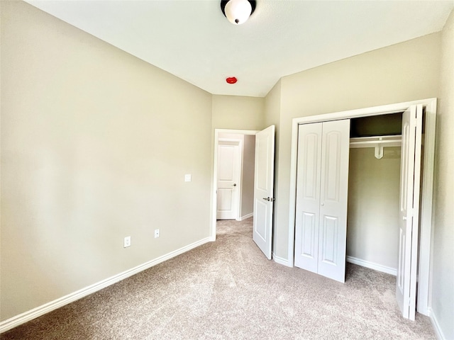 unfurnished bedroom featuring carpet, baseboards, and a closet