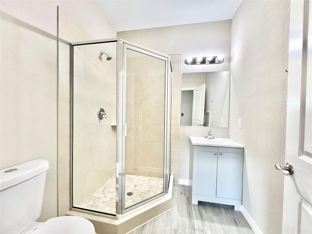 full bath featuring a shower stall, toilet, vanity, and wood finished floors