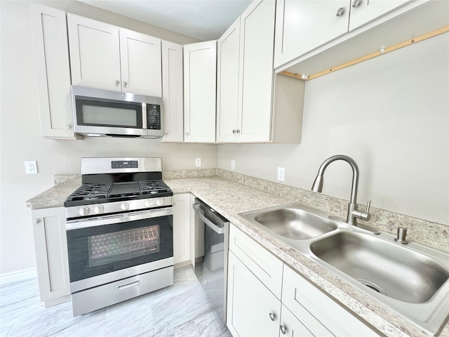 kitchen with a sink, stainless steel appliances, white cabinets, and light countertops