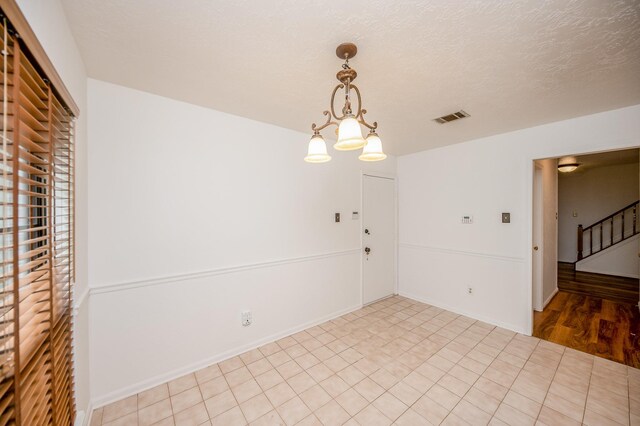 spare room featuring a notable chandelier and a textured ceiling