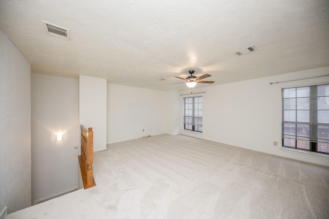 carpeted empty room featuring ceiling fan and a textured ceiling