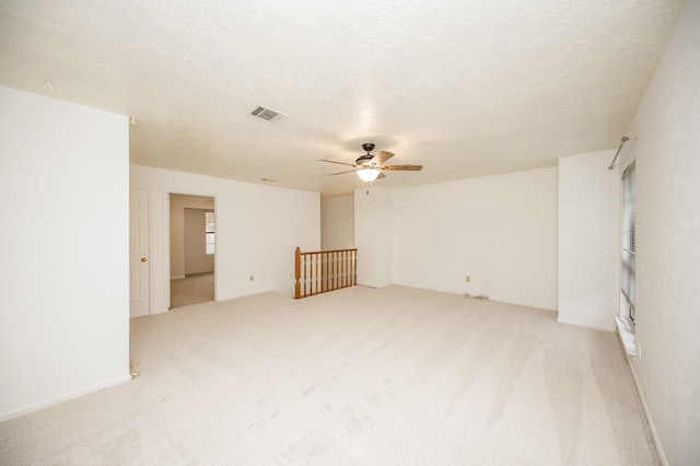 unfurnished room with ceiling fan, light colored carpet, and a textured ceiling