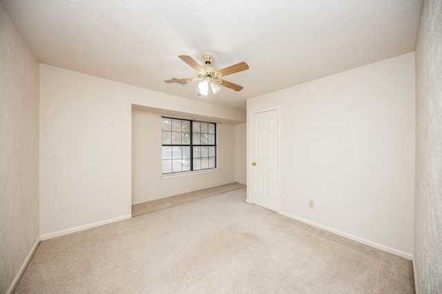 spare room featuring a textured ceiling, light colored carpet, and ceiling fan