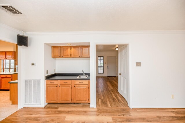 kitchen featuring crown molding, sink, and light hardwood / wood-style flooring